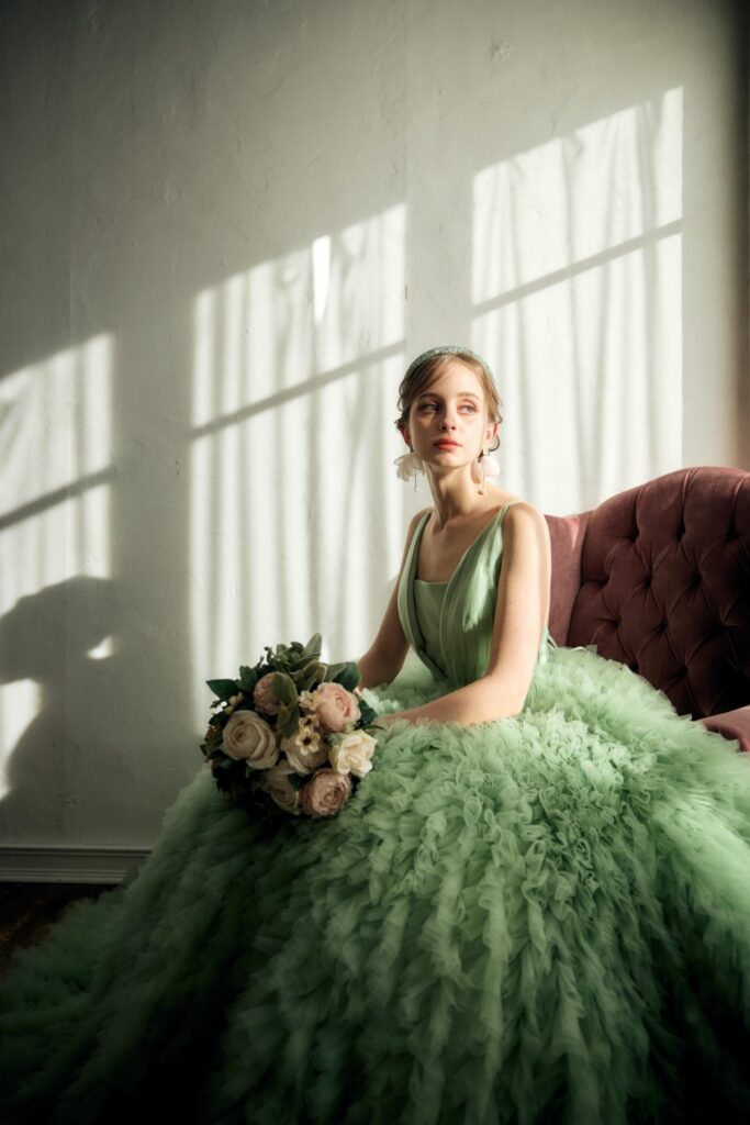 窓際の光に映えるグリーンのカラードレスを着用したプレ花嫁様