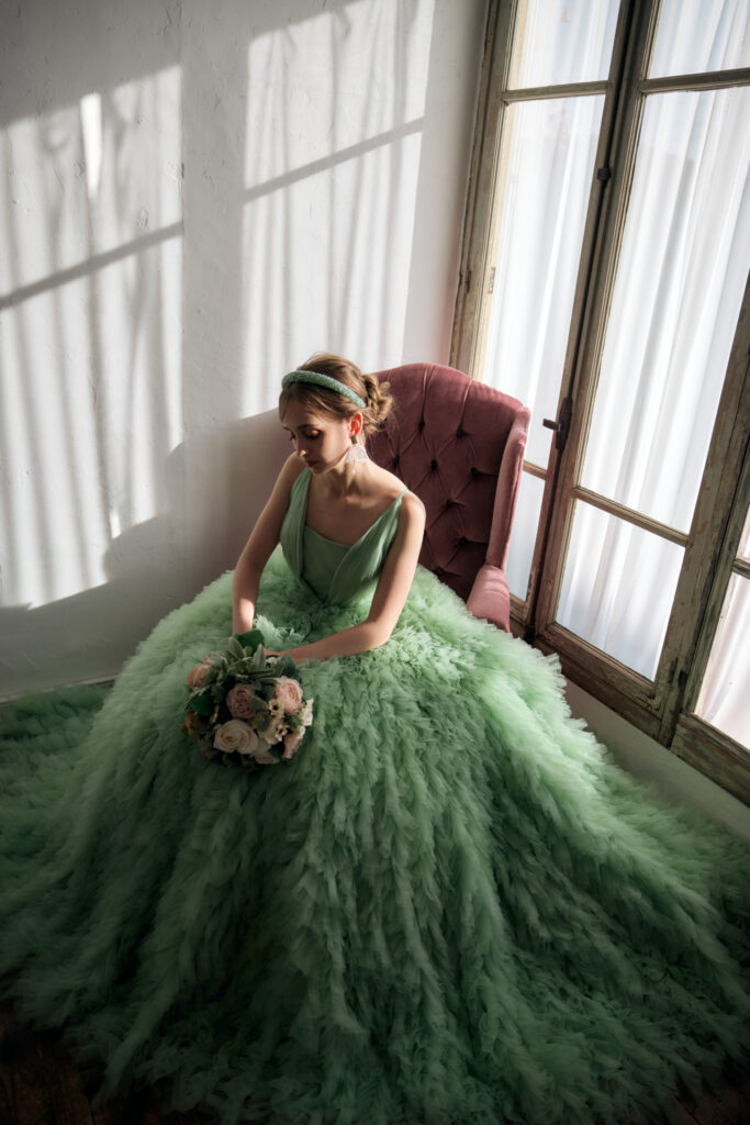 落ち着いた雰囲気で座る、緑のカラードレスを纏ったプレ花嫁